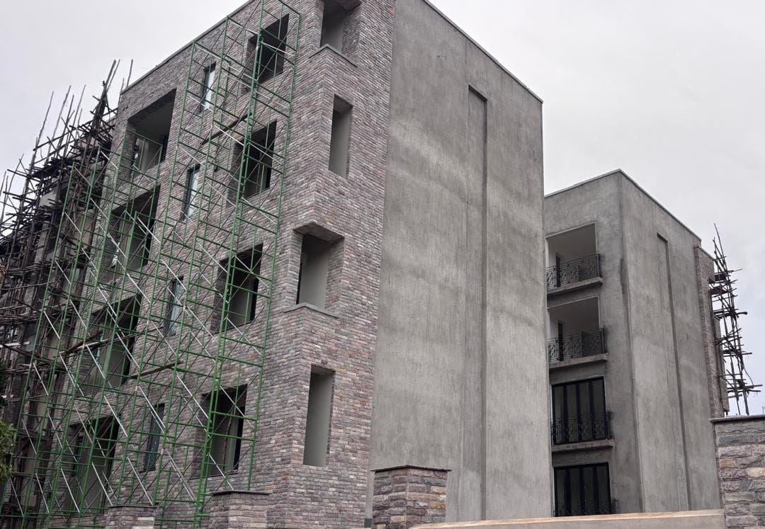 Stone-clad apartment building and adjoining rendered wing with scaffolding