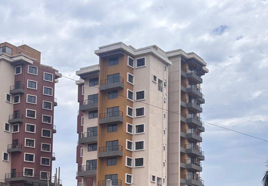 Brown, cream and maroon apartment towers with stacked balconies beneath a cloudy sky