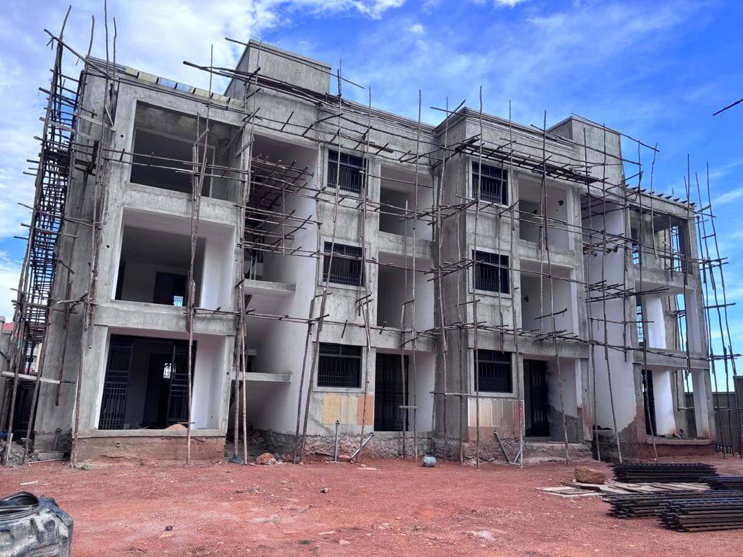 Concrete apartment block with open balconies, barred openings and timber scaffolding